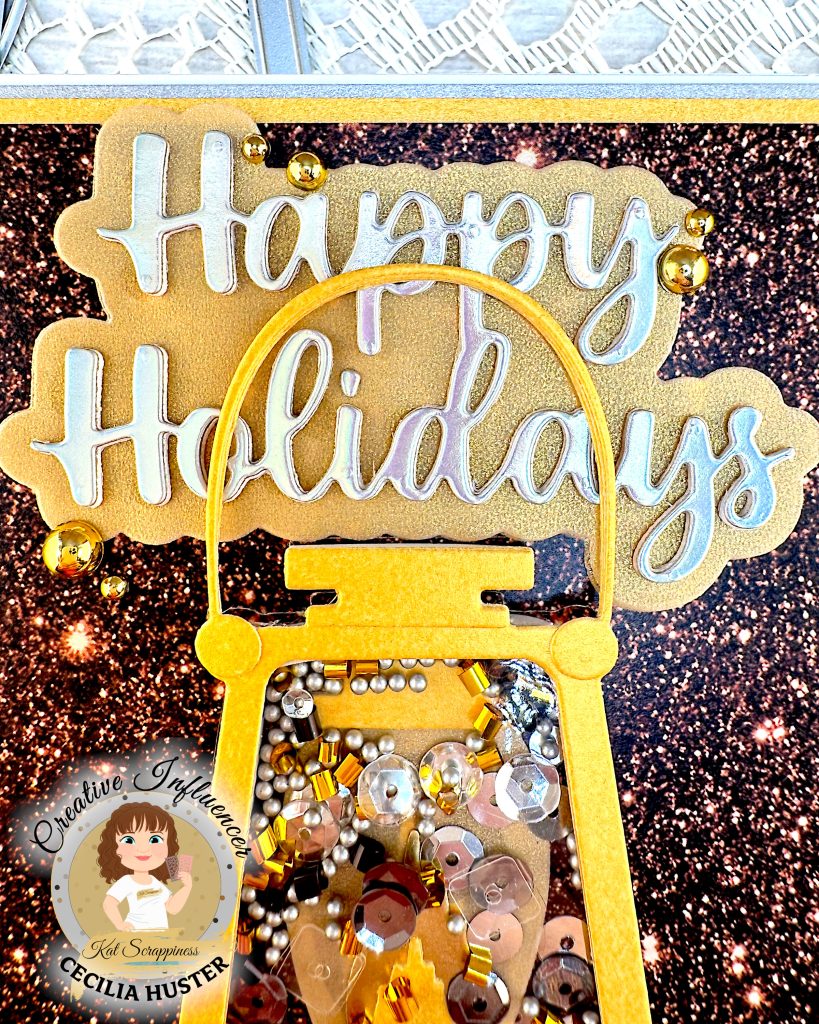 Closeup of the sentiment on a greeting card in gold and silver tones. It reads "Happy Holidays." The word is made up of a silvery cardstock and it has an ample shadow layer in gold pearlized vellum. Some gold flat back pearls have been glued around it.