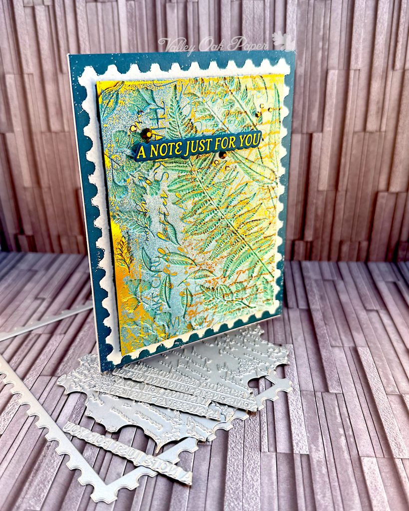 Greeting card in blue and gold tones on a slate grey background. The greeting reads "A note just for you." The card stands on some of the press plates used to create it.