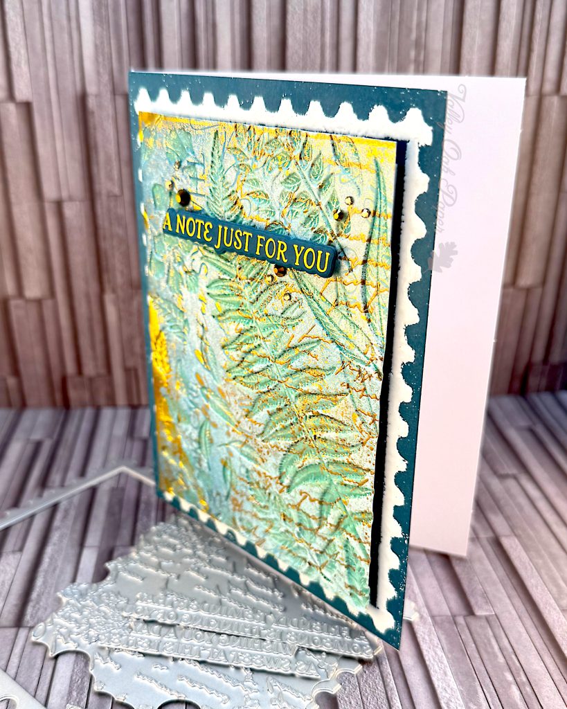 Greeting card in blue and gold tones on a slate grey background. The greeting reads "A note just for you." The card is standing up facing to the right.