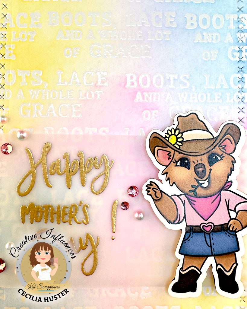 Closeup of the center of the card. You can make out that the background has been repeatedly stamped with the sentiment "Boots, Lace and a Whole Lot of Grace."