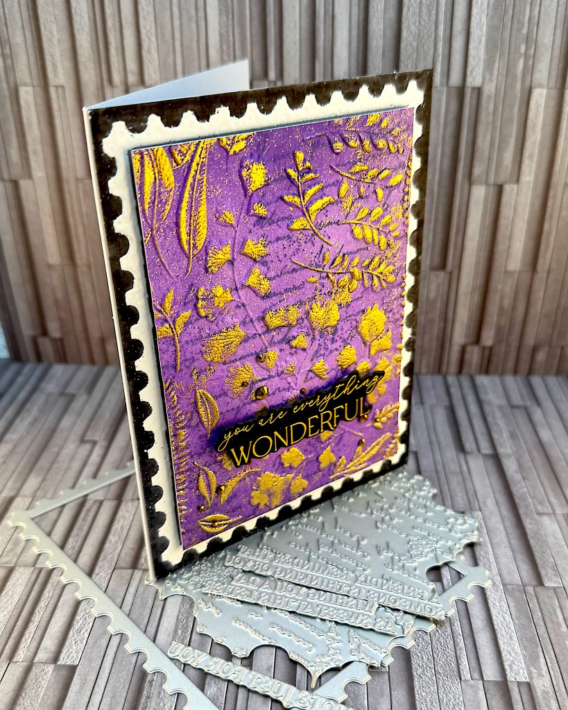 A black greeting card seen from an angle. A purple postage stamp is taking up most of the space. The greeting reads "You are everything wonderful." This is against a slate grey background.