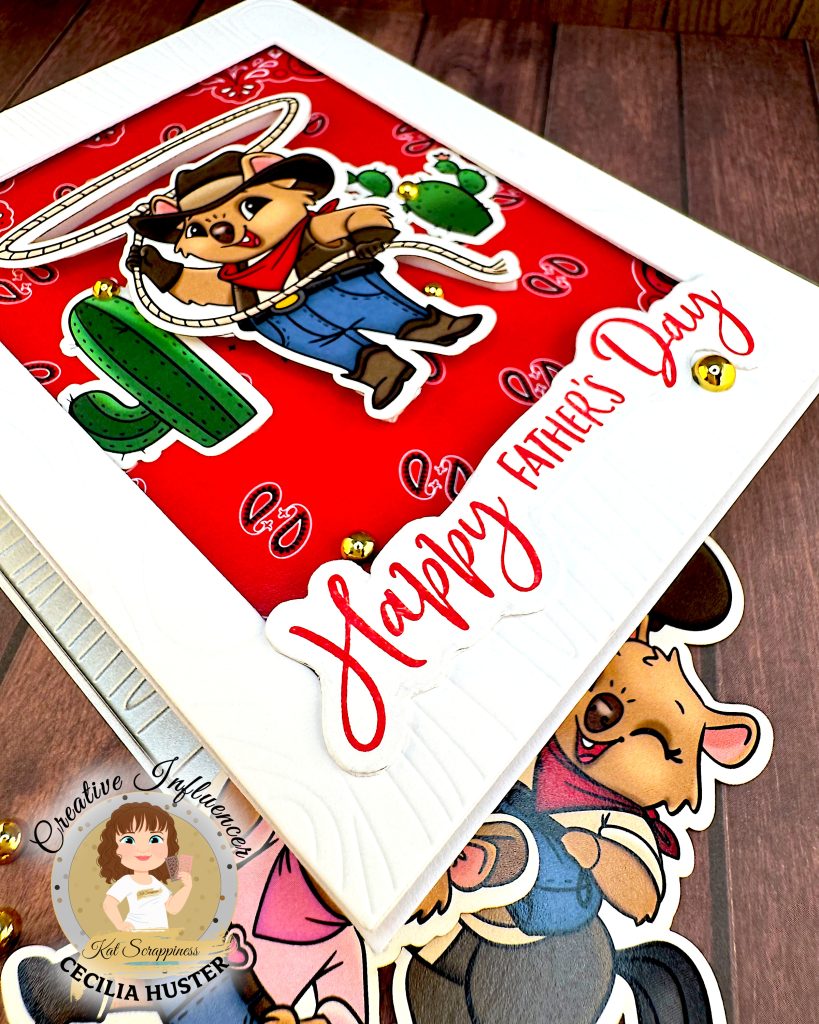 A Father's Day greeting card featuring a cute cartoon cowboy quokka character wearing a black cowboy hat, red bandana, and blue overalls. He is twirling a lasso with cacti in the background. The card has a red patterned background and "Happy Father's Day" text in red script lettering.
The scene is photographed at an angle from the bottom left corner on a wooden surface with cowboy-quokka-themed ephemera and gold beads. This angle allows you to see the topography of the card. The red bandana background is recessed behind the frame with the quokka character appearing to hover above it.
There's a watermark for "Kat Scrappiness Creative Influencer CECILIA HUSTER" in the bottom left corner.