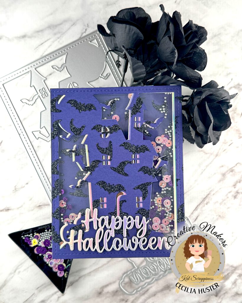 A shaker greeting card in purple, black and silver is pictured against a marble background. The card has an overall pattern of black glitter witchy hats and bats. The motif is a haunted house. Against the background we can see sequins in purple and silver tones. The silver sentiment reads Happy Halloween. 

The cover die, sentiment die and sequins that were used to create the card are also displayed. In addition, some black roses can be seen. In the lower right corner is a watermark that reads Creative Maker Cecilia Huster for Kat Scrappiness. 