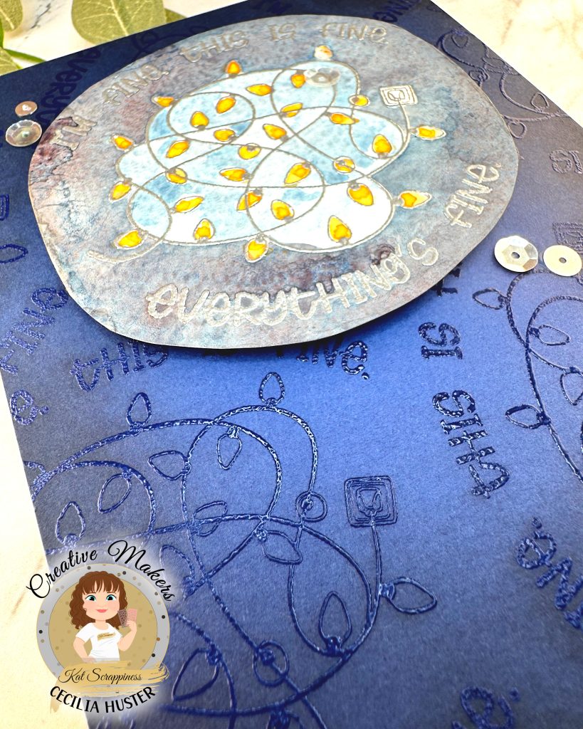 A handmade greeting card with a navy background. The main feature of the card is a watercolor panel showing a tangled light string with lights in amber.
The text around the image says "I'm fine. This is fine. Everything's fine." A few silver sequins adorn the card front.
The card has been photographed on a marble background with salvia leaves. The lower left corner is closest to the camera. This emphasizes the background pattern that repeats the main motif embossed with clear powder.
In the lower left corner is a watermark with the text "Creative Maker for Kat Scrappiness: Cecilia Huster."