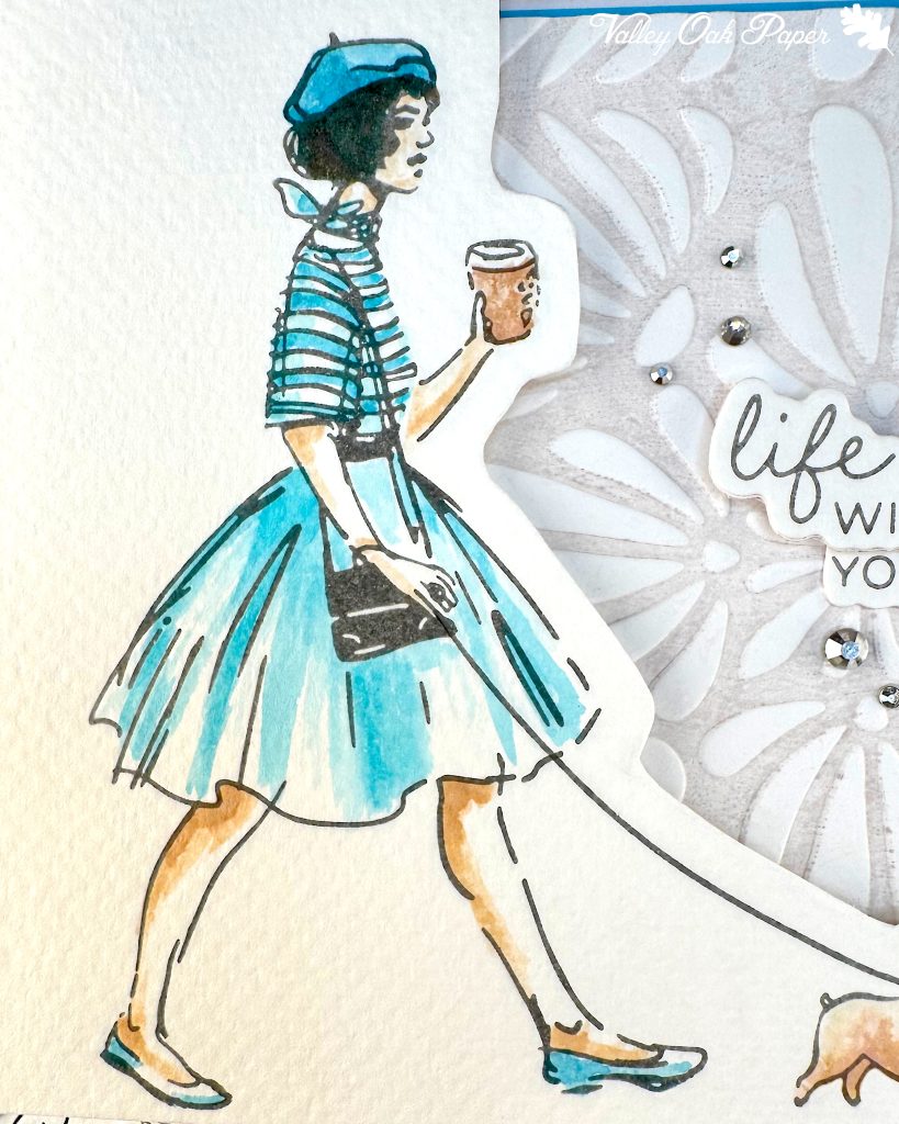 A handmade greeting card featuring an illustration of a woman walking a small fat dog and holding a coffee cup. The illustration has been watercolored in turquoise and brown tones in a loose style.
The background is embossed with an organic, floral pattern.